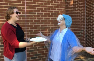 Diane Valade laughs after a student hist her int he face with a pie. Photography by Teriney Grooms