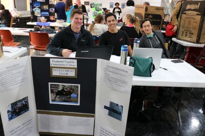 students pose at investment club table with posters