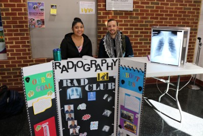 Students pose with posters at club day table