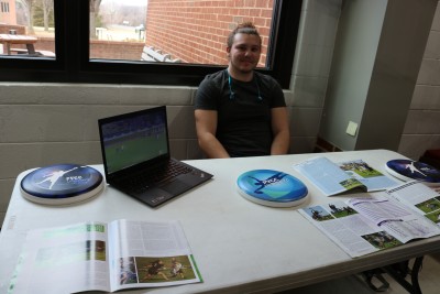 student poses at club day table with frisbee 