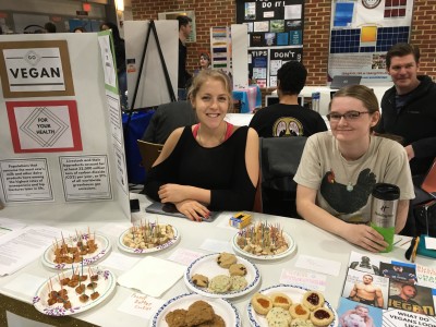 students pose with vegan food at the club day table