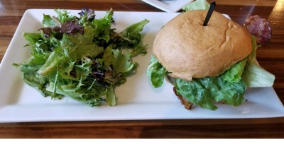 An “Original Burger” topped with bacon, lettuce, mayo, house sauce, and tomato; every hamburger comes with a salad on the side. Photography by Richard Hollis. 