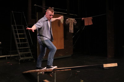 Shane Rose posing on a seesaw set piece during rehearsal. Photography by Madison Weikle 