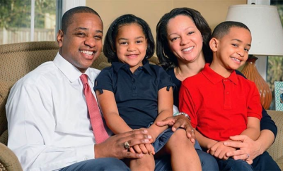 Fairfax family smiles on a couch. Photo Courtesy of Fairfax website