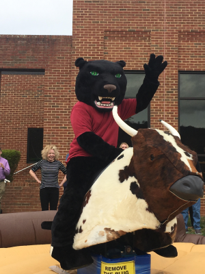 PVCC mascot Pouncer rides a mechanical Bull at the Spring Fling.