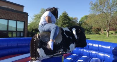 A person holds on to a mechanical bull. 
