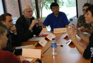 Students and community members talk around a table