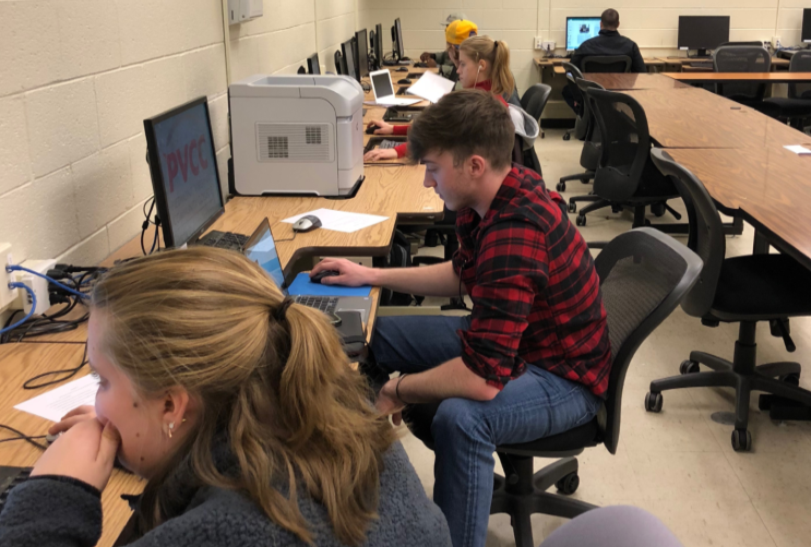 Students working on computers assembling issues for The Forum