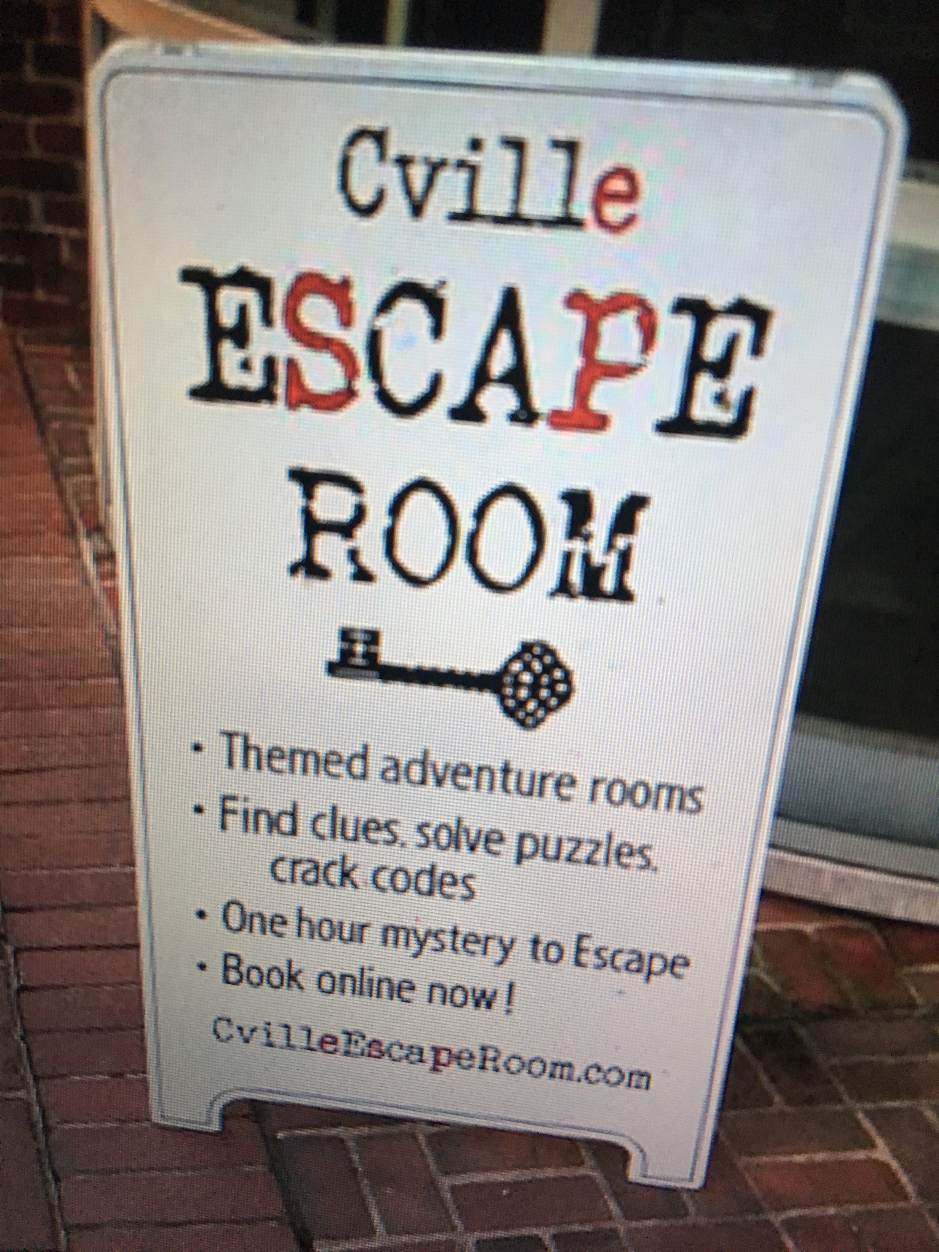 C-Ville Escape Room sign on brick. Various text.