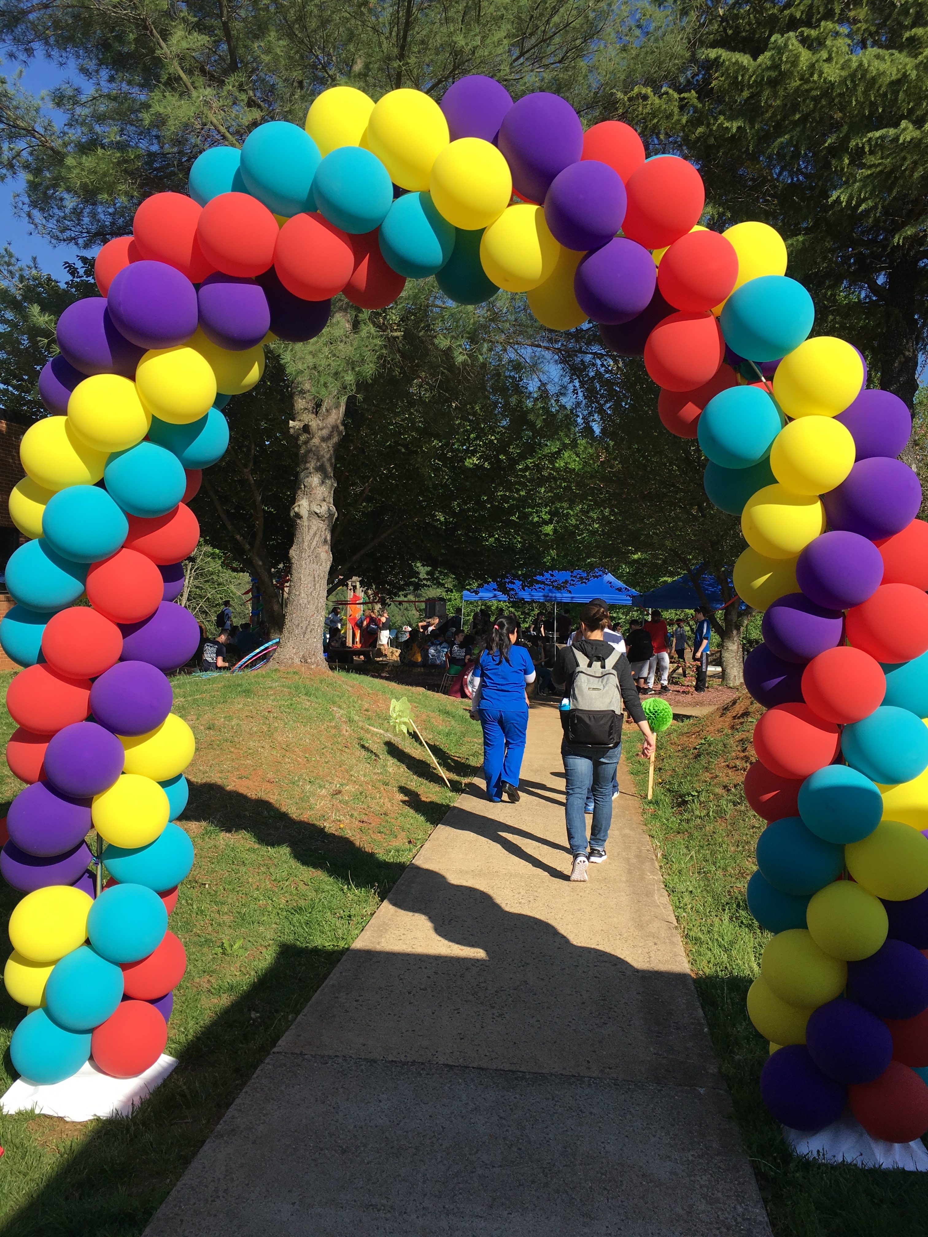 People attending Spring Fling pass under a colorful balloon arch.