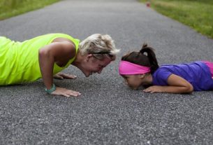 An older woman doing pushups with a young girl in the street