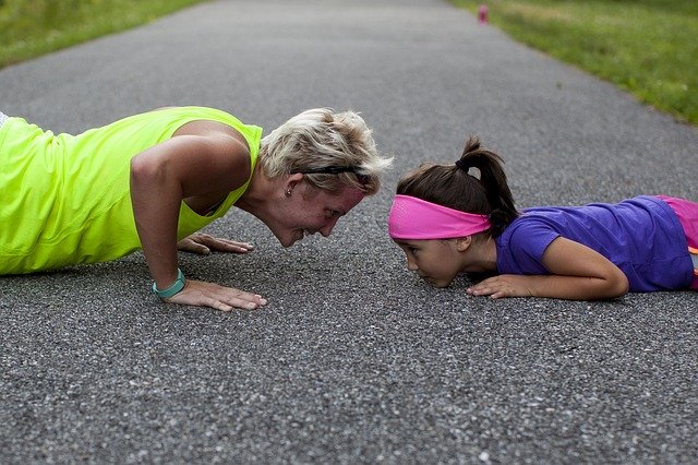 An older woman doing pushups with a young girl in the street