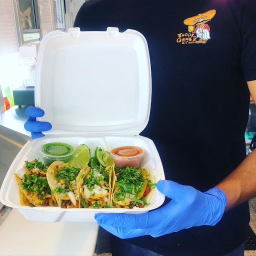 Four tacos in a white takeout container.