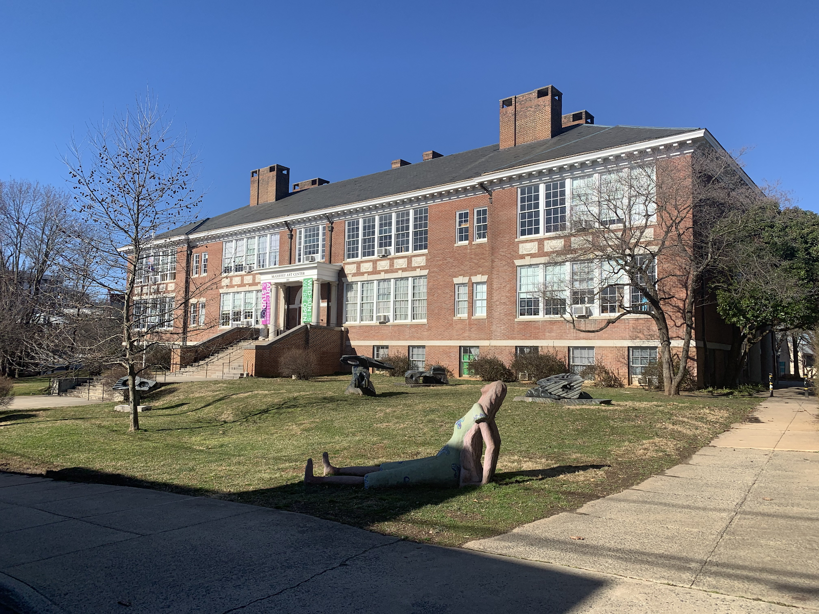 A photo of the McGuffey Art Center, a large brick building with an assortment of statues on the lawn out front