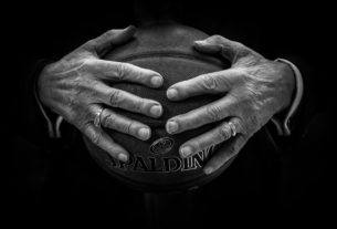 A pair of hands hold a basketball in a black and white image