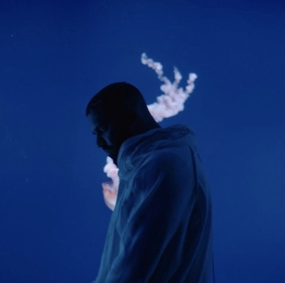 A man stands silhouetted against a blue background