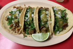 Several tacos sit on an oval shaped plate