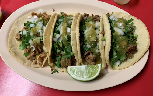 Several tacos sit on an oval shaped plate