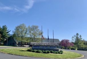 View of the main entrance sign for the museum adorner with flags and flowers