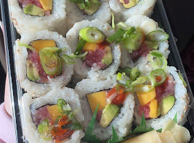 A tray of twelve sushi rolls, each one made up of tuna, sriracha sauce, mango and more,