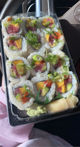 A tray of twelve sushi rolls, each one made up of tuna, sriracha sauce, mango and more,