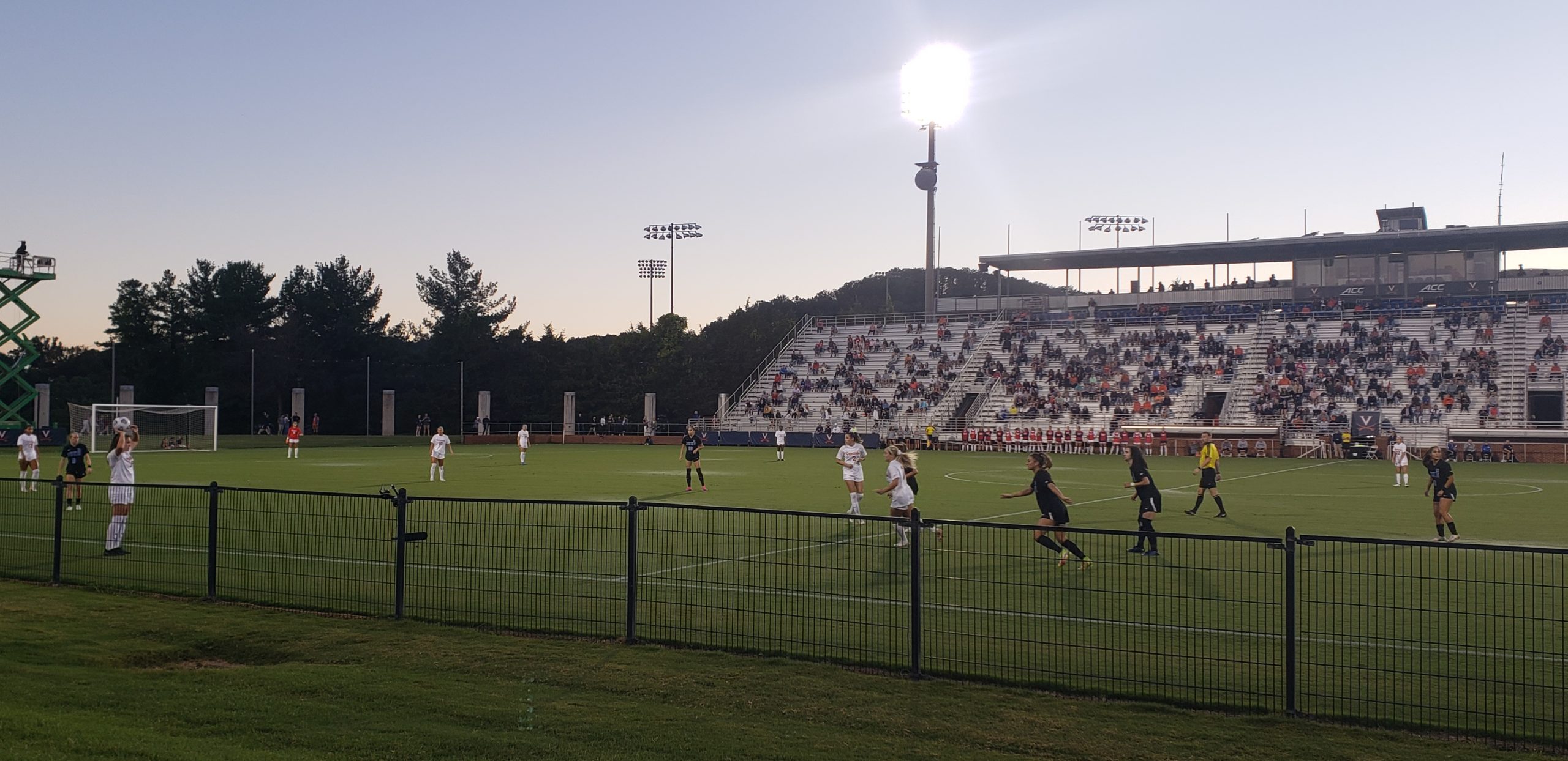 Members of the UVA Women's soccer team, clad in white jerseys, face off against the opposing Duke women's soccer team