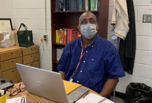 Academic Coach James Bryant, clad in a blue shirt,sits in his chair at the writing center