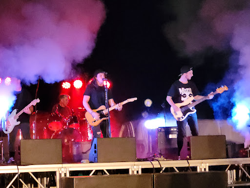 Three guitarists and one drummer on a stage surrounded by smoke during Charlottesville's battle of the bands