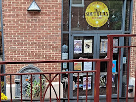 The front entrance of the Southern Cafe, a brick building with two double glass doors with a yellow logo on a glass window above the entrance