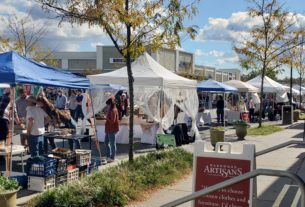 A line of various outdoor tents sell their wares to crowds of customers at the Craft Cville Pop-up Market