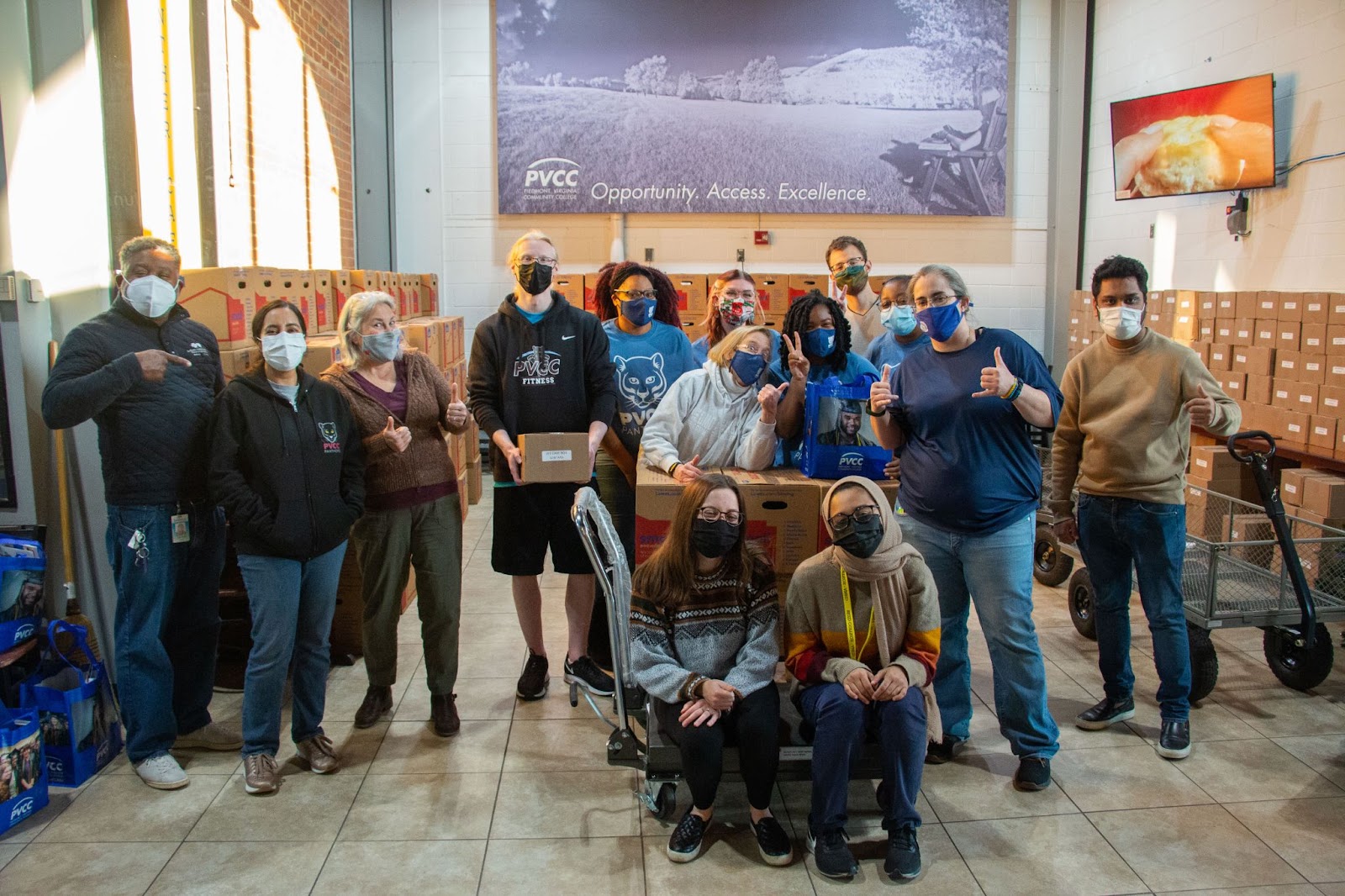 Volunteers and PVCC Faculty pose in front of the Panther Cafe, with numerous boxes in the background.