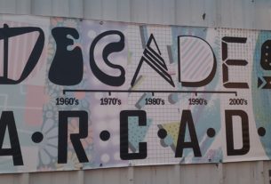 A vintage sign with Decade Arcade's name in varrying black letters
