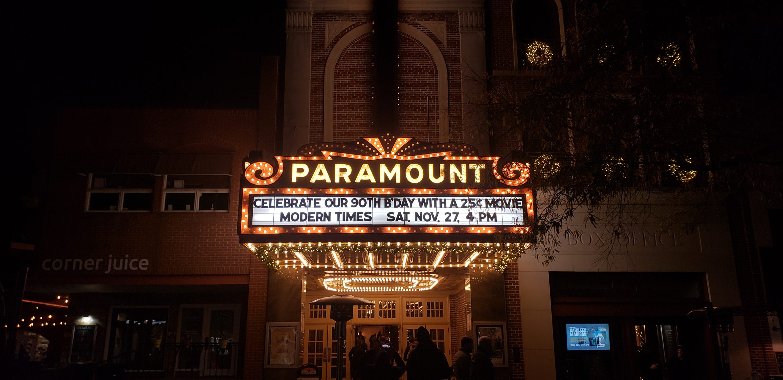 The glowing neon sign of the paramount theater in downtown Charlottesville, reading "celebrate our 90th birthday with a 25 cent movie, modern times"