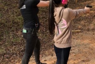 Clara Elliot and student (left to right) stand on a firing line aiming handguns at a target that is out of frame.