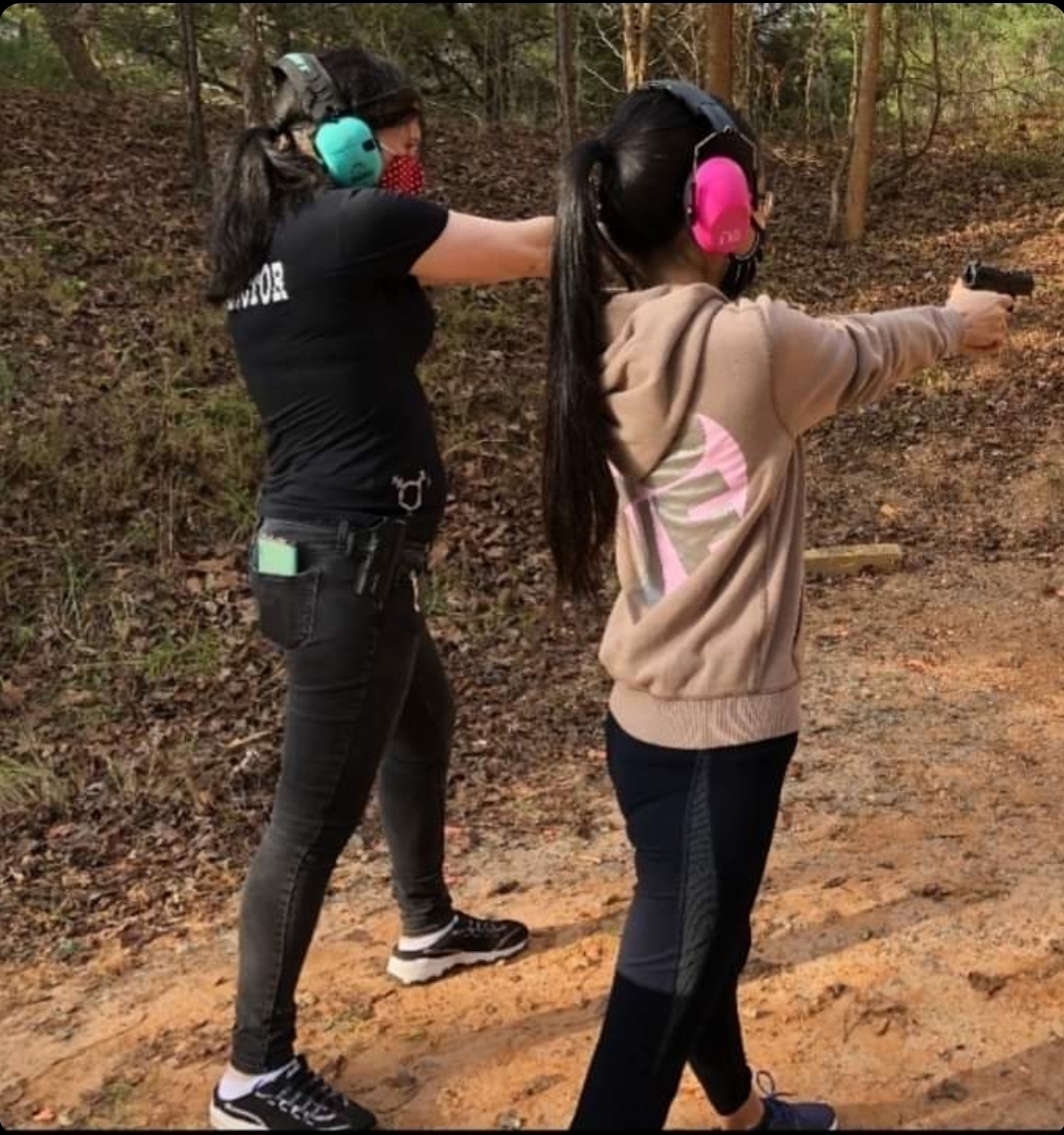 Clara Elliot and student (left to right) stand on a firing line aiming handguns at a target that is out of frame.