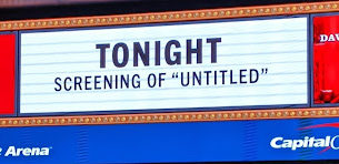 A white sign above a movie theater reading "Tonight screening of 'untitled" in large black letters