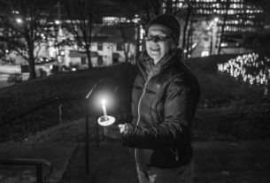 A black and white photo of Fenella Belle holding a candle at the 2021 PVCC Let There Be Light Exhibit