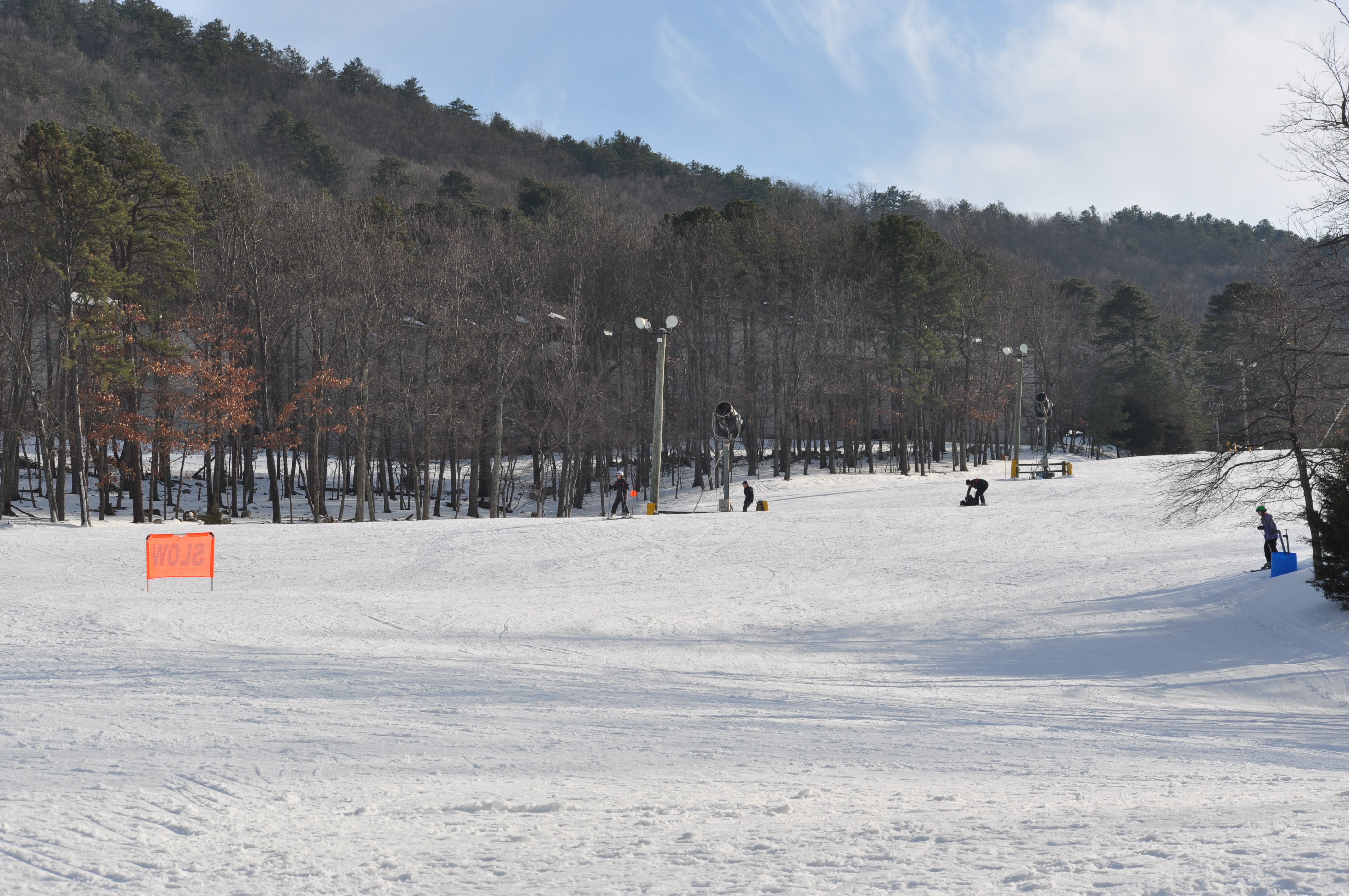 A photo looking up a large white ski slope with trees around it.