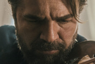 A close up photo of a man playing the violin