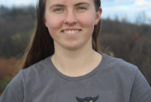 Laurel Molloy poses for a picture wearing a shirt with a black cat on it.