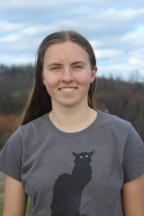 Laurel Molloy poses for a picture wearing a shirt with a black cat on it.