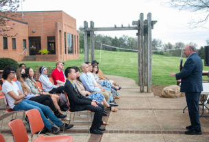 Frank Friedman speaks to a group of students sitting in chairs on the student patio on a cloudy day