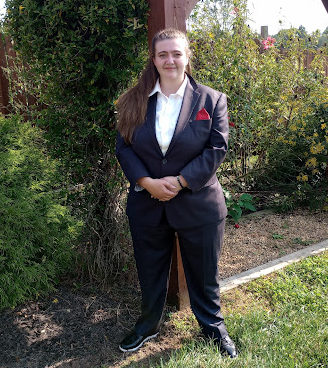 A woman wearing a suit smiles standing in a garden