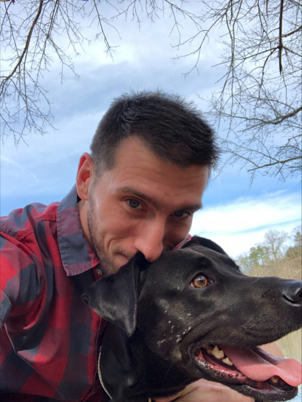 Philosophy professor Stephen Marrone smiling with his dog while outside.