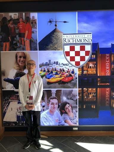 Johnson Li standing in front of University of Richmond photo highlights inside the Queally Center of Admissions.