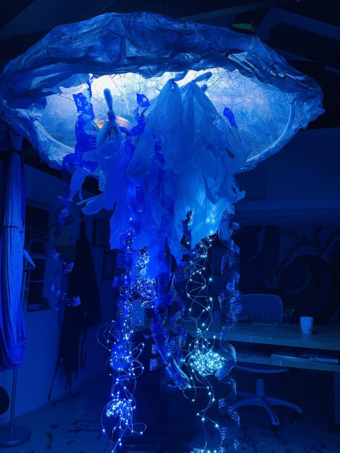 A blue sculpture of a jellyfish with lights shining in it