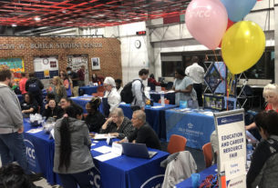 The Bolick Student Center crowded with tables. Fair goers converse with department representatives sat at these tables. A sign in the foreground reads "Education and Career Resource Fair"