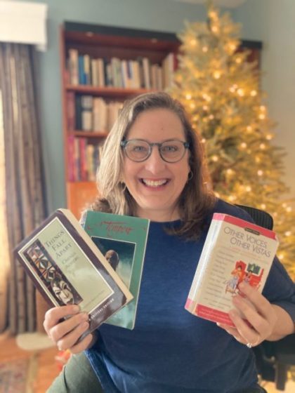 woman poses in front of Christmas Tree holding three world literature books