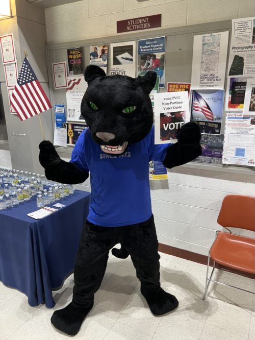 Pounce the Panther, the college mascot is posing with an American flag in his right hand and a voter guide in his left hand