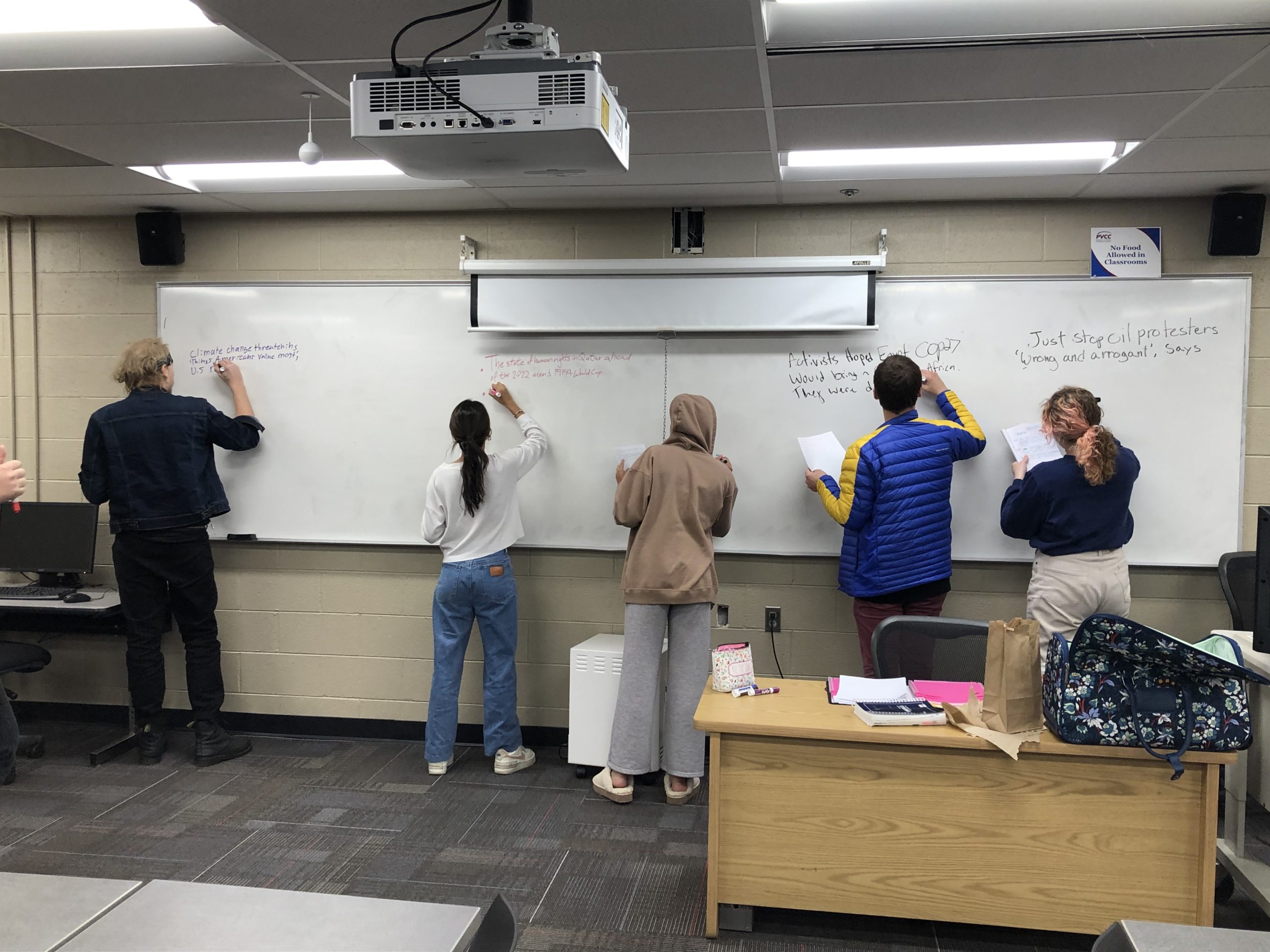 Students writing on a whiteboard in a group